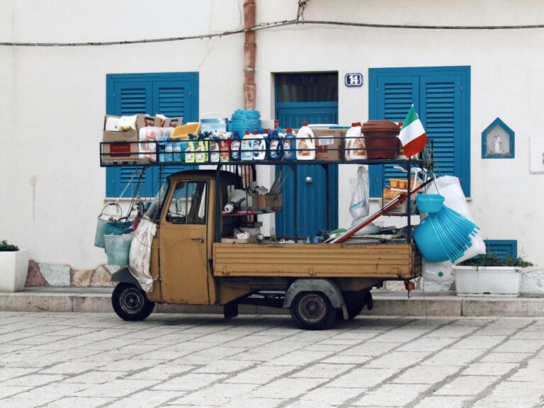 A small utility vehicle loaded with cleaning supplies in an urban street setting.